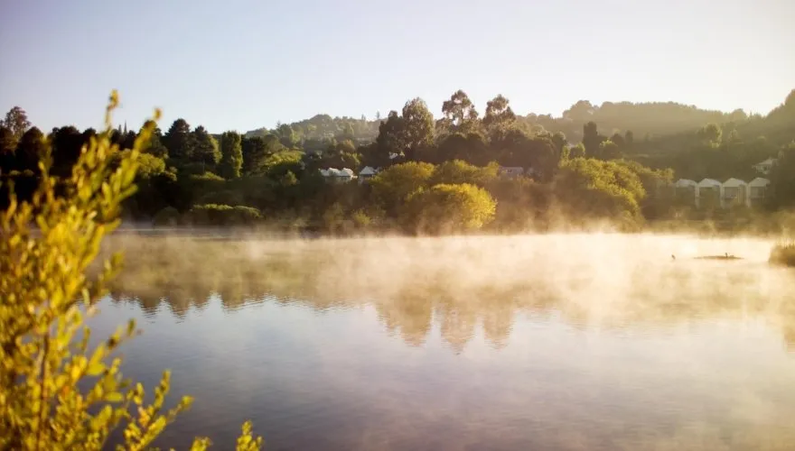 Morning mist rising over Lake Daylesford, with Lake House nestled among the trees