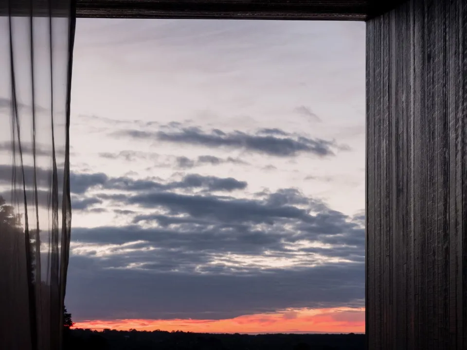 Sunset through charred timber from a vineyard-facing room