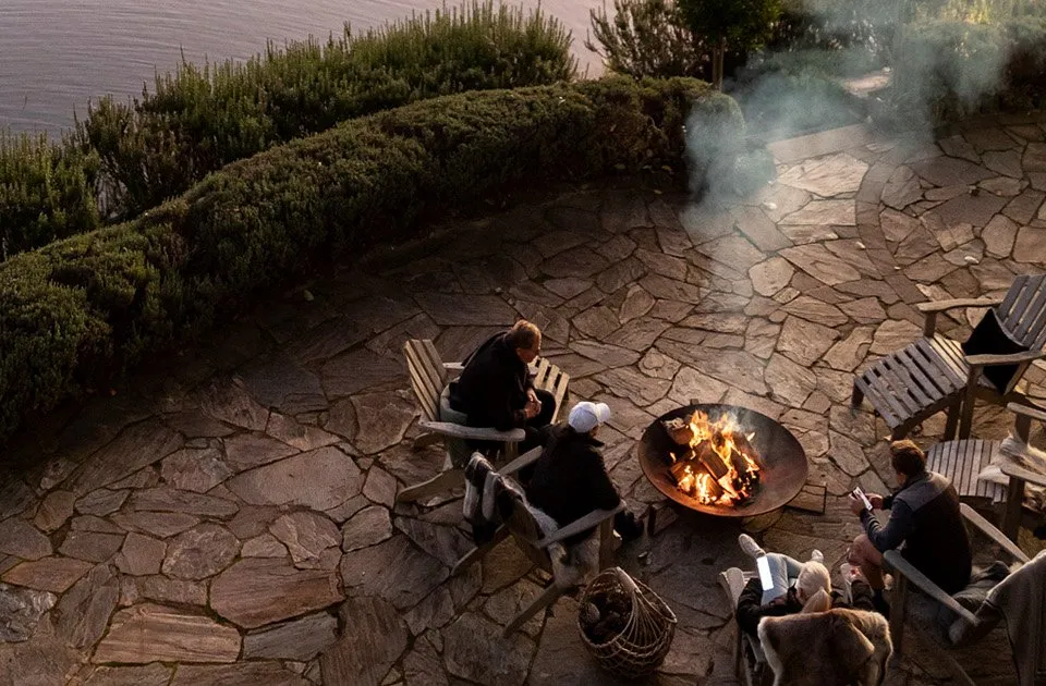 Guests gathered around the lakeside fire pit at dusk